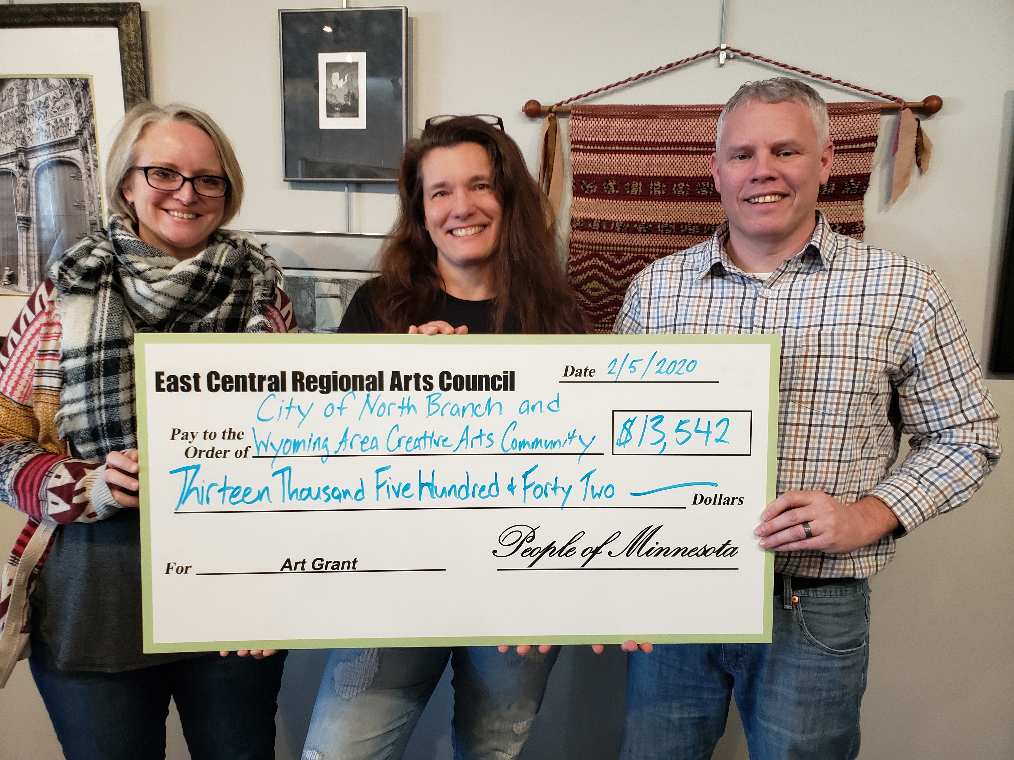 Tree Croyle and Jess Eischens of the Wyoming Area Creative Arts Community and Nate Sondrol of the City of North Branch accept funding for art projects.